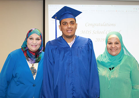 A student from the Marcia D Smith School poses for the camera with his family during his graduation ceremony.