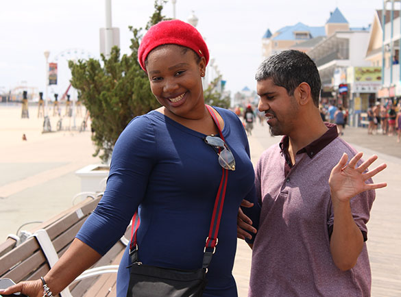 A person supported by a staff pose for the camera on the Ocean City Boardwalk.